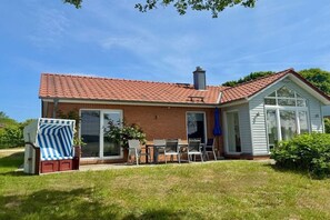 A two-story house with a red-tiled roof, a brick exterior, and a glass door entrance. - Marina Hülsen - The Willow River House (Kosel)