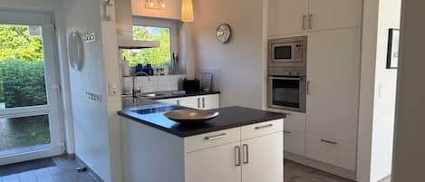 A modern kitchen with white cabinetry, a black countertop, and stainless steel appliances.