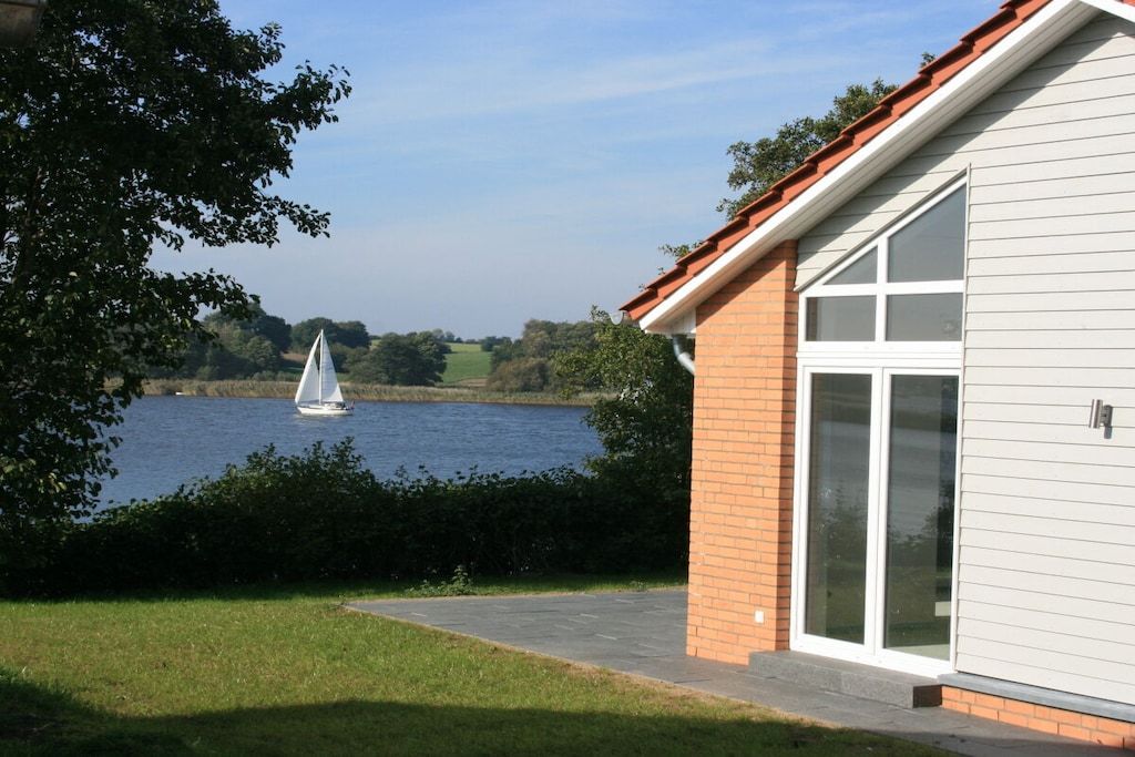 A house with a view of a lake and a sailboat.