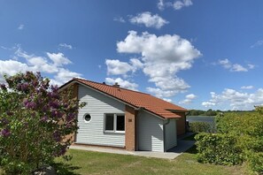 Une maison de plain-pied avec un toit recouvert de tuiles rouges, une petite fenêtre et une porte de garage.