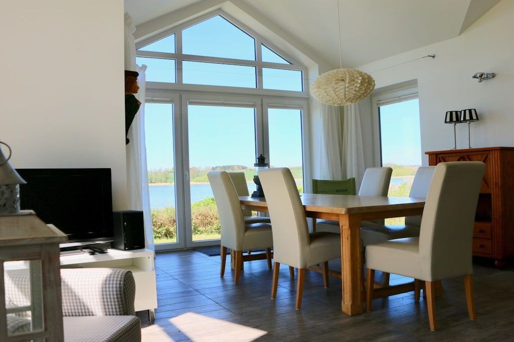 A dining area with a table and chairs, a television, and a view of the outdoors.