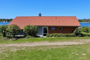Ein eingeschossiges Haus mit rotem Ziegeldach, einer Haustür und zwei runden Fenstern.