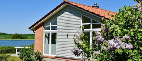 Ein Haus mit rotem Dach, großen Fenstern und Seeblick.