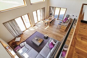 A spacious living area with a dining table, sofa, and large windows. - Holiday home in Pellworm with swimming pool (Pellworm)