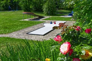 A park with a paved area, a metal bench, and a flower bed with roses. - Holiday home in Pellworm with swimming pool (Pellworm)