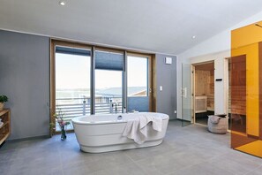 A modern bathroom with a freestanding bathtub, a glass shower enclosure, and a view of the outdoors. - Holiday home in Pellworm with swimming pool (Pellworm)
