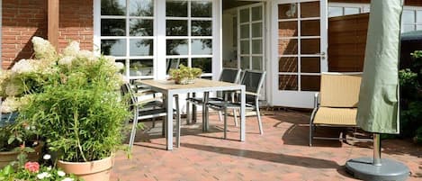 A patio with a table and chairs, a potted plant, and a folding screen.