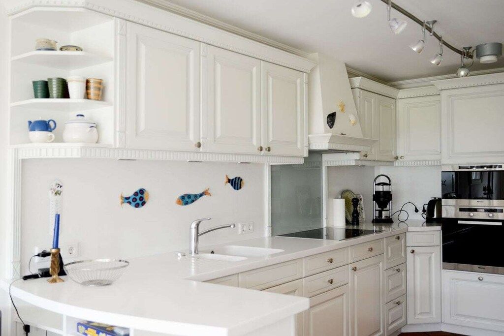 A kitchen with white cabinetry, a double sink, and a stove.