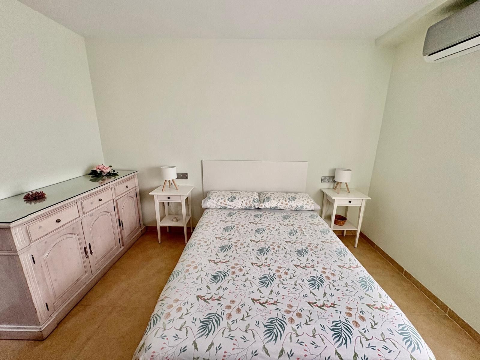 A bedroom with a bed, bedside tables, a dresser, and a mirror.