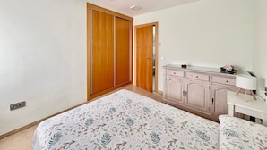 Quarto com cama, guarda-roupa, escrivaninha e abajur.