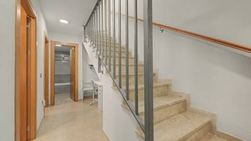 A staircase with a metal handrail and wooden steps, leading to a room with a white wall and a door.