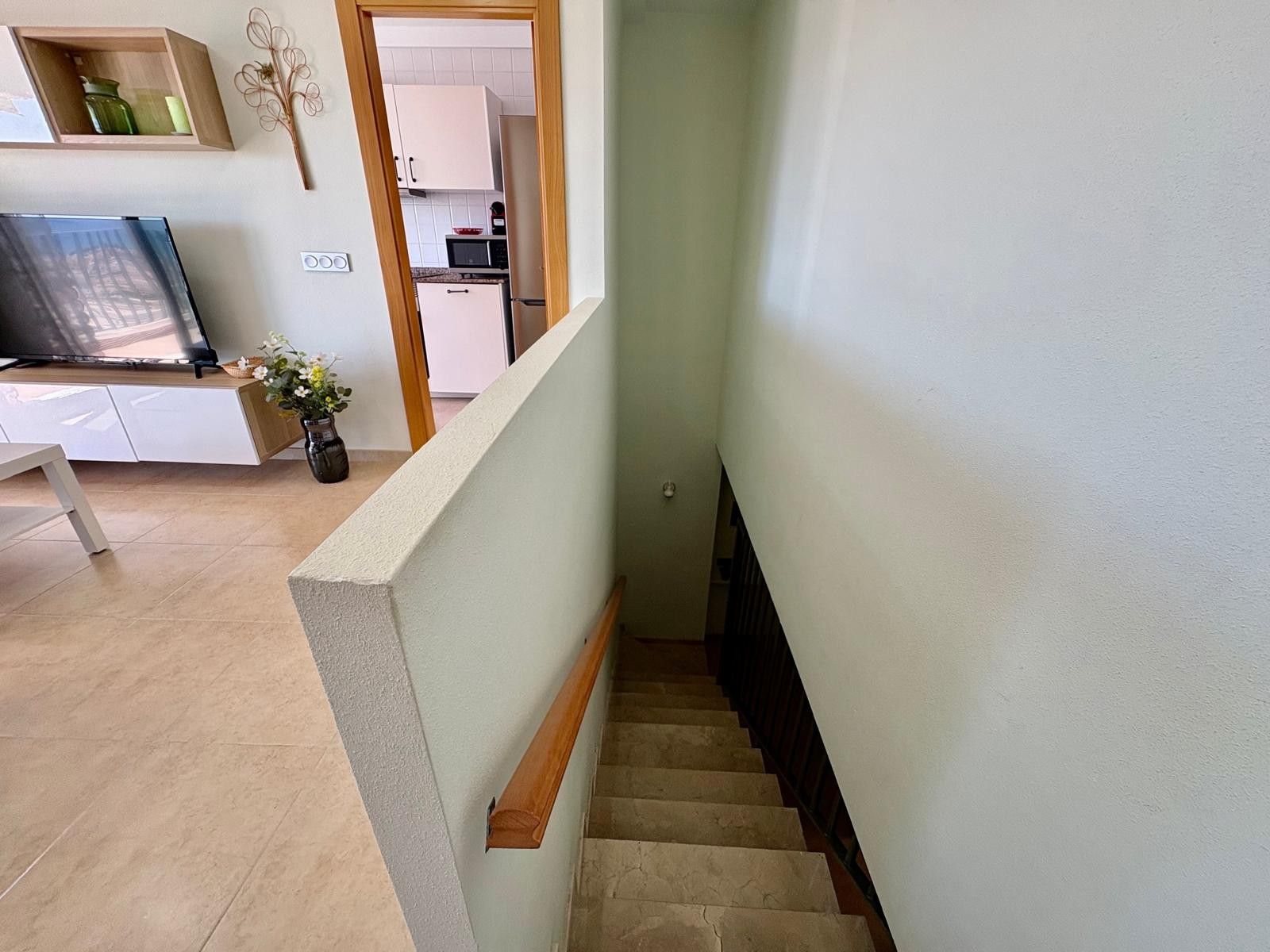 A staircase leading to a kitchen area with white cabinets and a microwave.