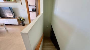 A staircase leading to a kitchen area with white cabinets and a microwave.