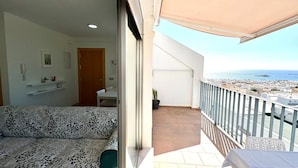 Varanda com vista para o mar, um sofá e uma mesa.