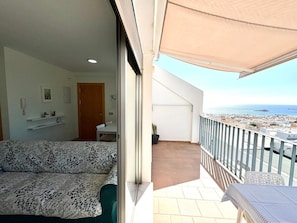 En balkon med udsigt til havet, en sofa og et bord.