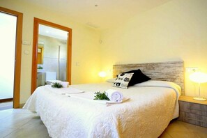 Une chambre d’hôtel avec un grand lit, une lampe de chevet, un miroir et une vue sur la salle de bain.