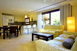 A modern living room with a sofa, coffee table, and dining area with chairs. - 44236 Modern beach house Es Baladre (Alcudia)