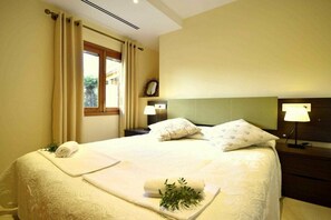 A hotel room with a bed, a nightstand, a lamp, a window with curtains, and a view of greenery outside. - 44236 Modern beach house Es Baladre (Alcudia)