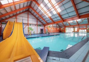 An indoor swimming pool with a yellow slide and a high ceiling with skylights. - Seaside Escape at St Osyth (Clacton-on-Sea)