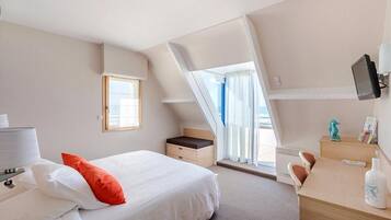 A hotel room with a bed, a desk, a chair, a television, and a window with curtains.