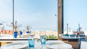 A table set for two with a view of the sea and boats in the background.