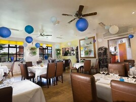 A restaurant with multiple tables and chairs, ceiling fans, and hanging paper lanterns.