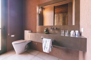 A bathroom with a toilet, sink, mirror, and towel rack. - Rosell Boher Lodge (Ugarteche)