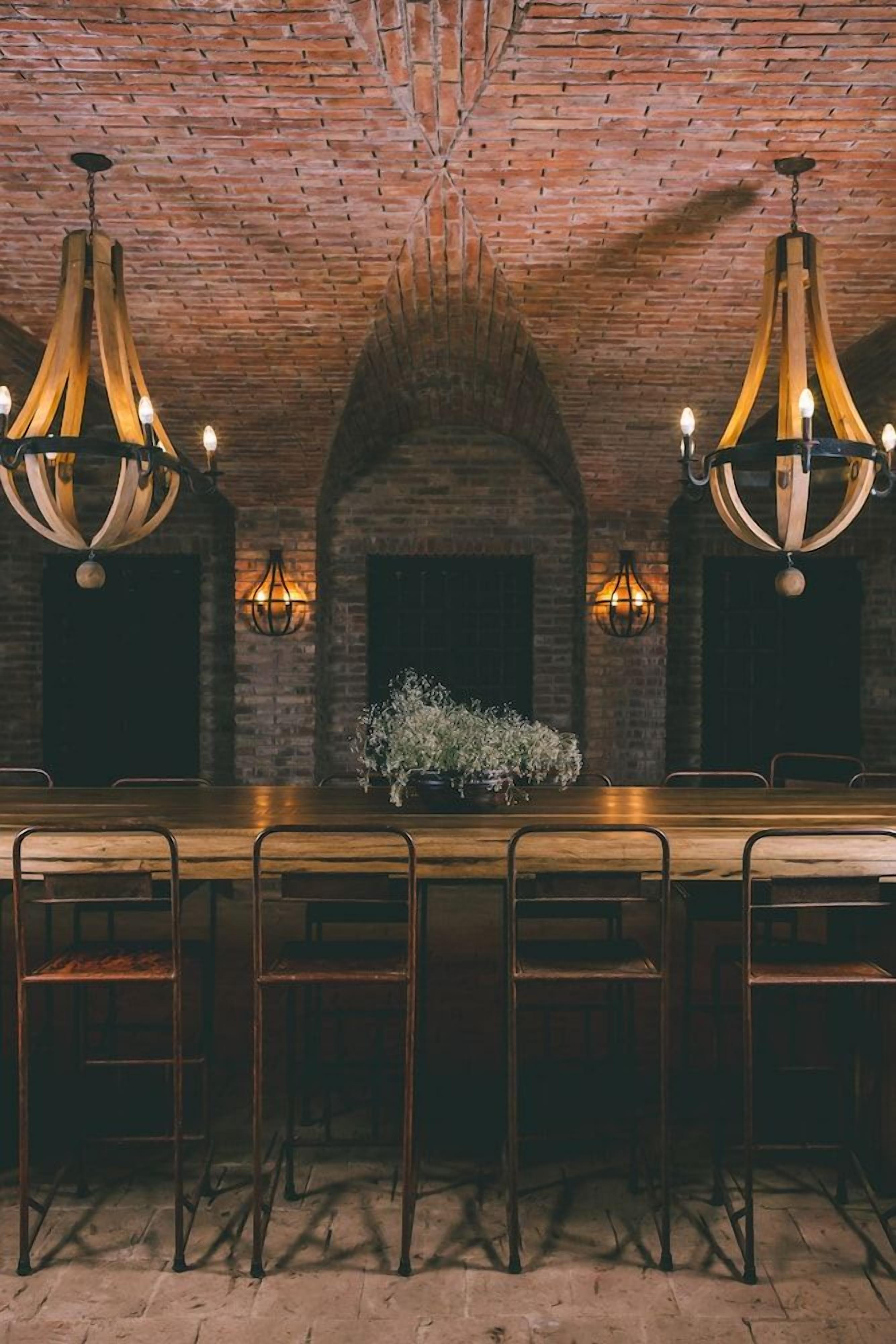 Zona de bar con pared de ladrillo, mostrador de madera y sillas de metal.