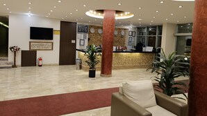 A hotel lobby with a reception desk, a flat-screen TV, a clock, and a fire extinguisher. - Truva Life Hotel (Samandagi)