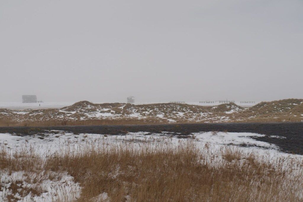 Un paysage enneigé avec un bâtiment qui se dessine à l'horizon.