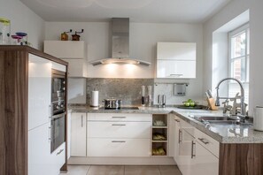 A modern kitchen with white cabinetry, granite countertops, and stainless steel appliances. - Holiday home with 1 bedroom (St. Peter - Ording)