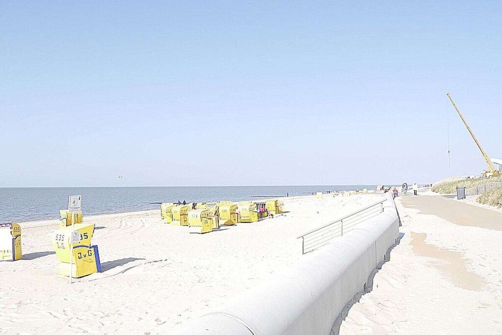 A beach with yellow lifeguard stands and a concrete barrier along the shoreline.