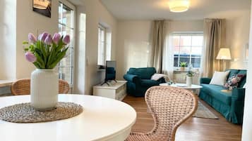 A modern living room with a round table, a sofa, and a wicker chair.