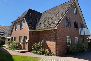 Ein zweistöckiges Backsteingebäude mit geneigtem Dach und einer kleinen Veranda. Auf der Seite ist die Nummer 2 gut sichtbar.