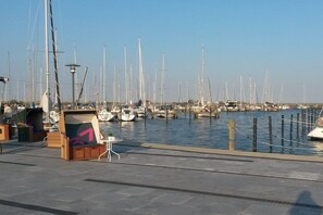 Ein Yachthafen mit vielen angestuften Segelbooten, eine Holzbank mit einer Nummer und ein klarer Himmel.
