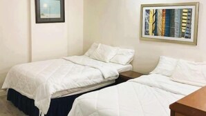 A hotel room with two beds, a framed picture on the wall, and a ceiling light. - Sawmill Inn (Hennessey)