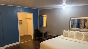 A hotel room with a bed, desk, chair, and a door leading to a bathroom. - Sawmill Inn (Hennessey)