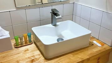 A bathroom with a white sink, a mirror, and a wooden countertop.