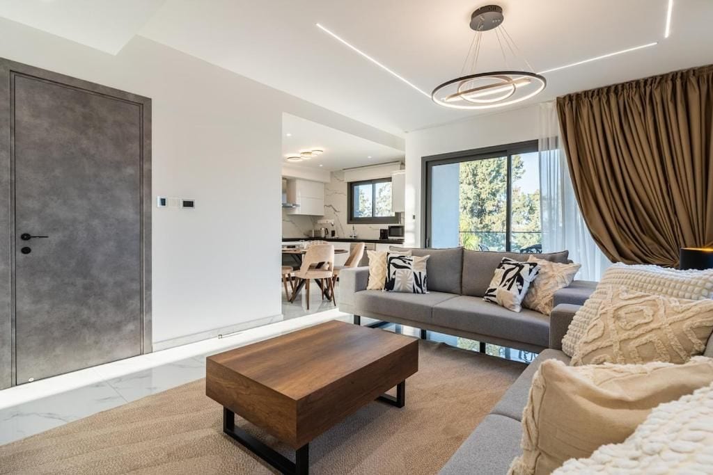 A modern living room with a sofa, coffee table, and a view of the kitchen.