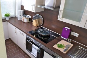A modern kitchen with a stove, oven, and various appliances. - Holiday apartment with 1 bedroom (St. Peter - Ording)