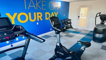 A gym with exercise equipment, a motivational wall, and a checkered floor.