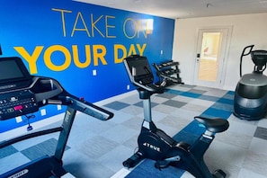 A gym with exercise equipment, a motivational wall, and a checkered floor.