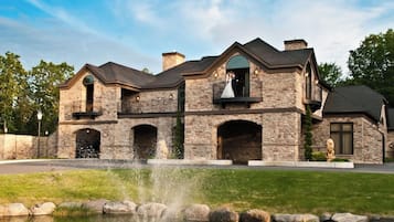 A stone house with a fountain, a balcony, and a statue.