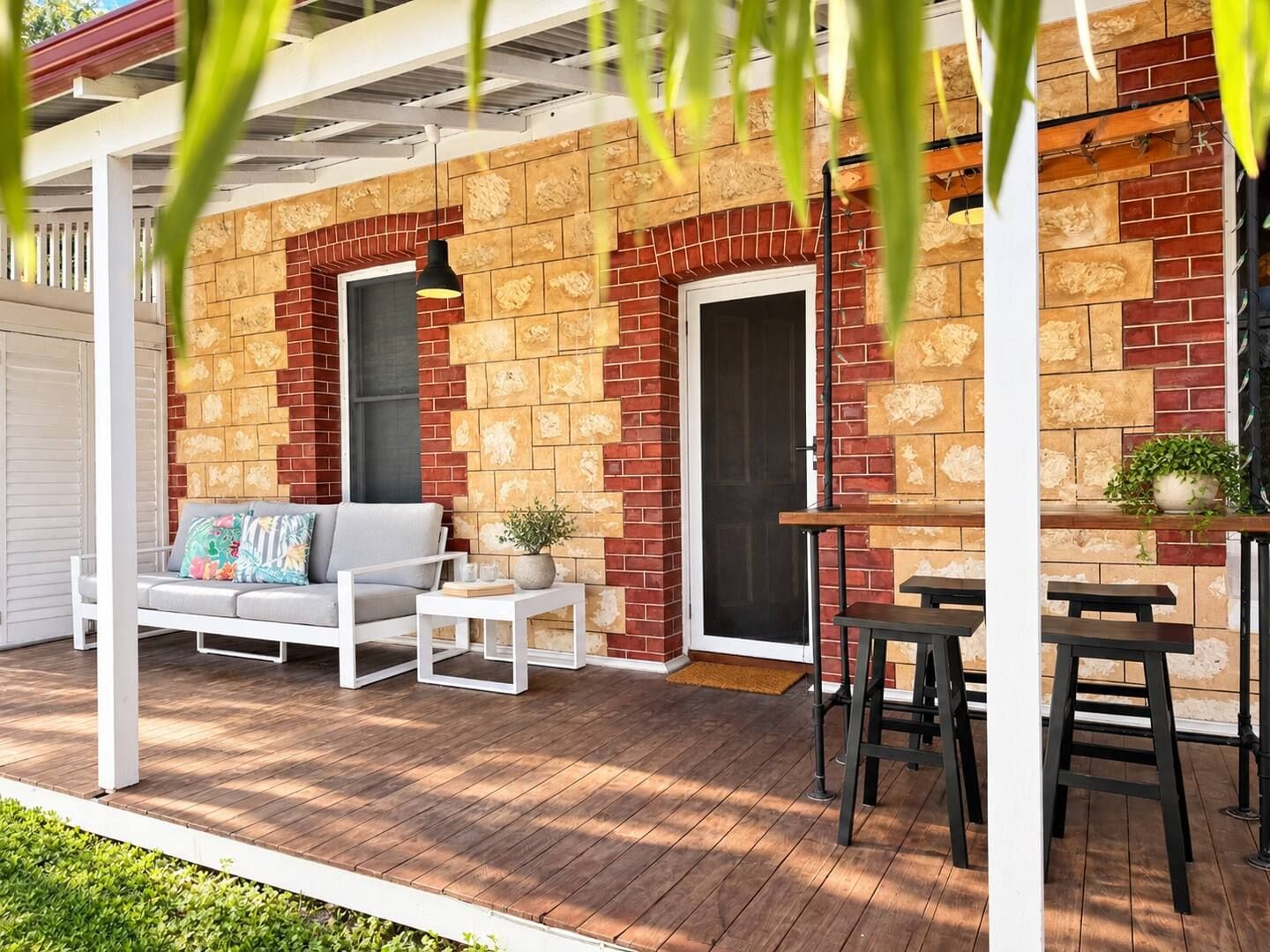 A covered outdoor seating area with a brick wall, a sofa, a table, and chairs.