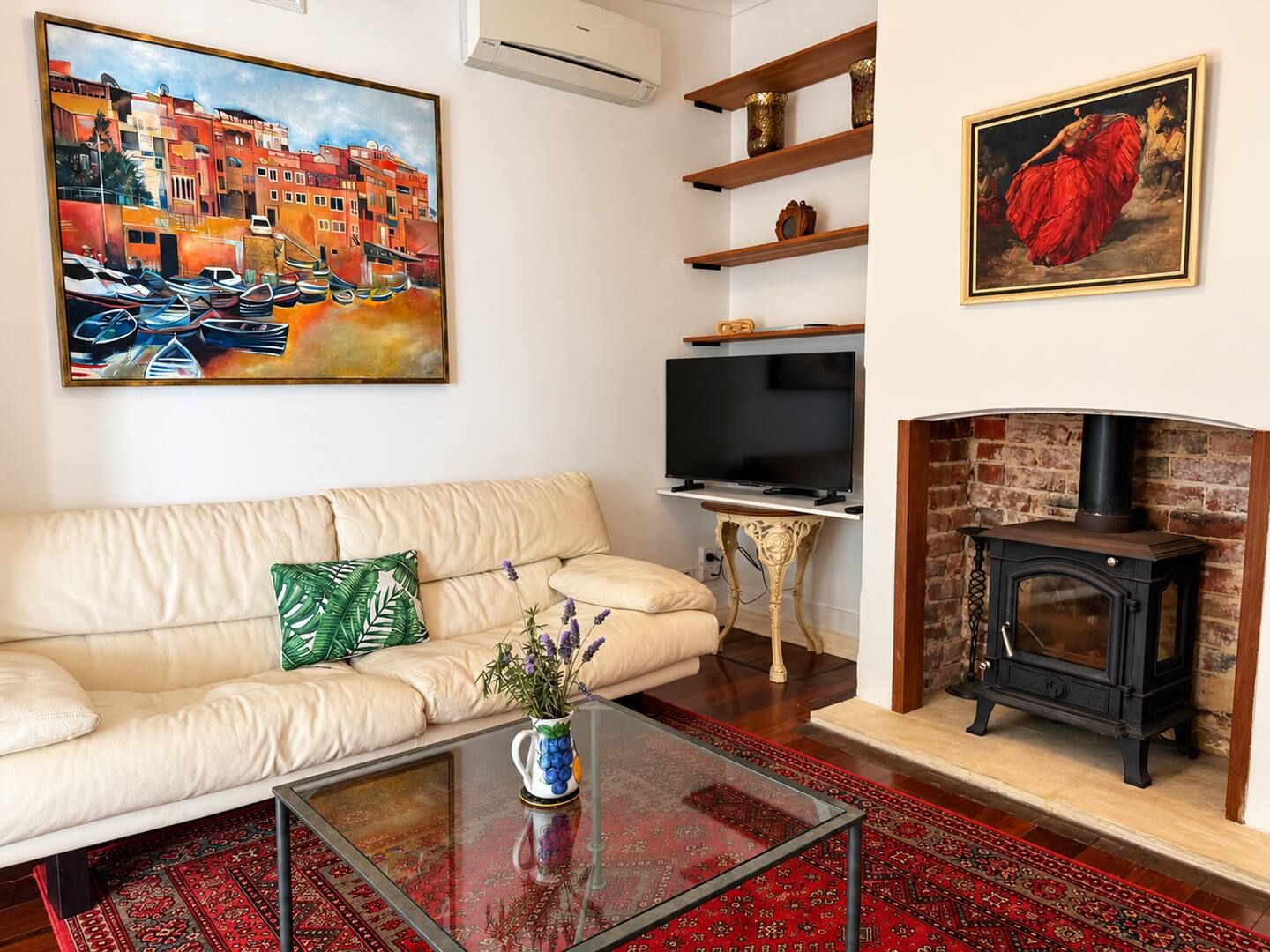 Un salon comprenant un canapé, une table basse, une cheminée, un téléviseur et des œuvres d’art accrochées aux murs.