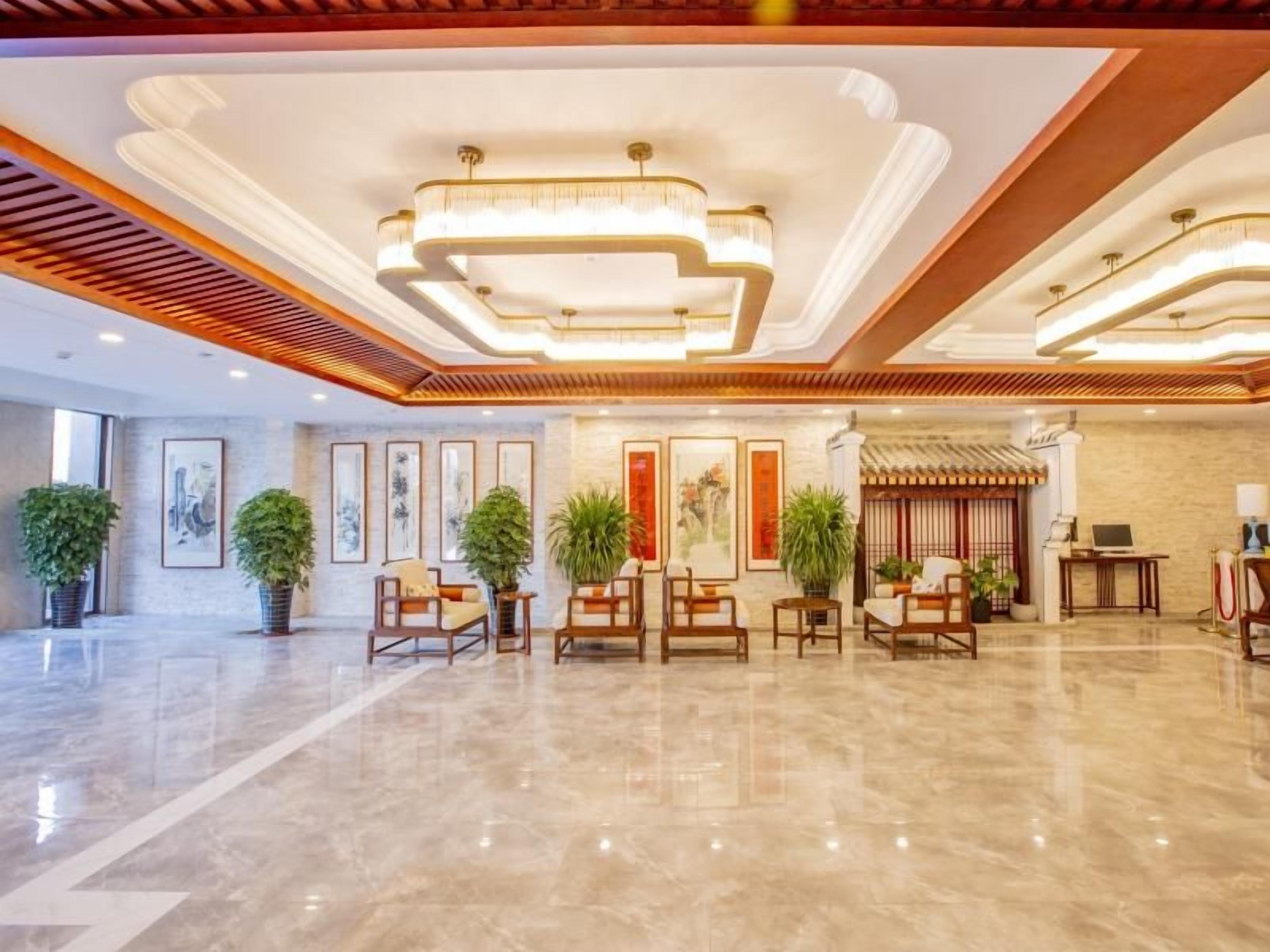 Un hall amplio con piso de mármol pulido, mobiliario de madera y una recepción de estilo tradicional.