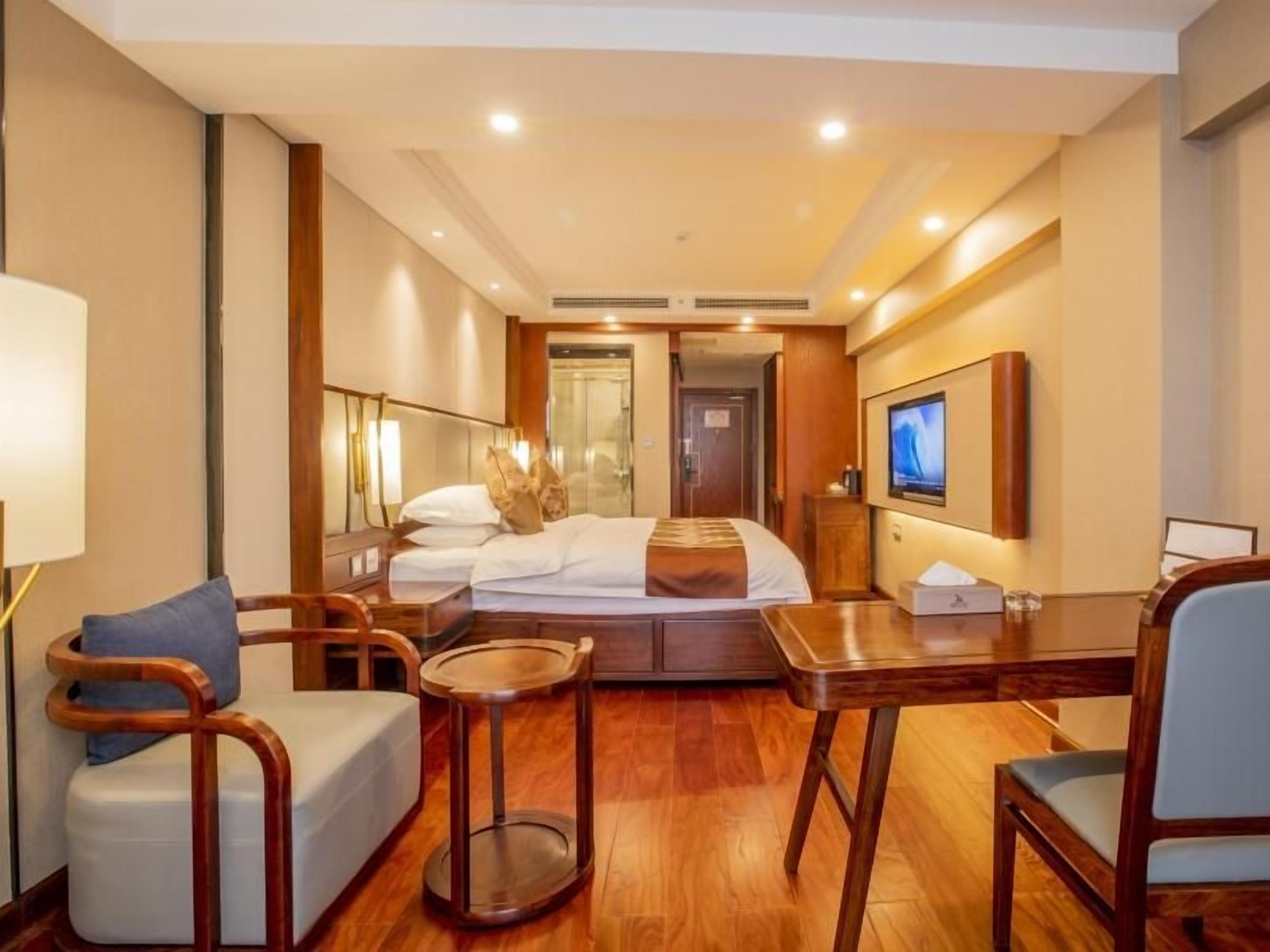 Una habitación de hotel con cama, escritorio, silla, mesita y televisor.
