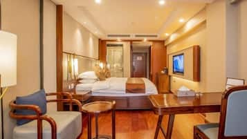 Una habitación de hotel con cama, escritorio, silla, mesita y televisor.