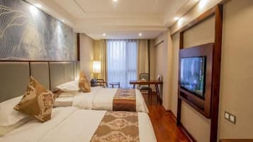 Ein Hotelzimmer mit einem großen Bett, einem Fernseher, einem Schreibtisch und einem Stuhl.