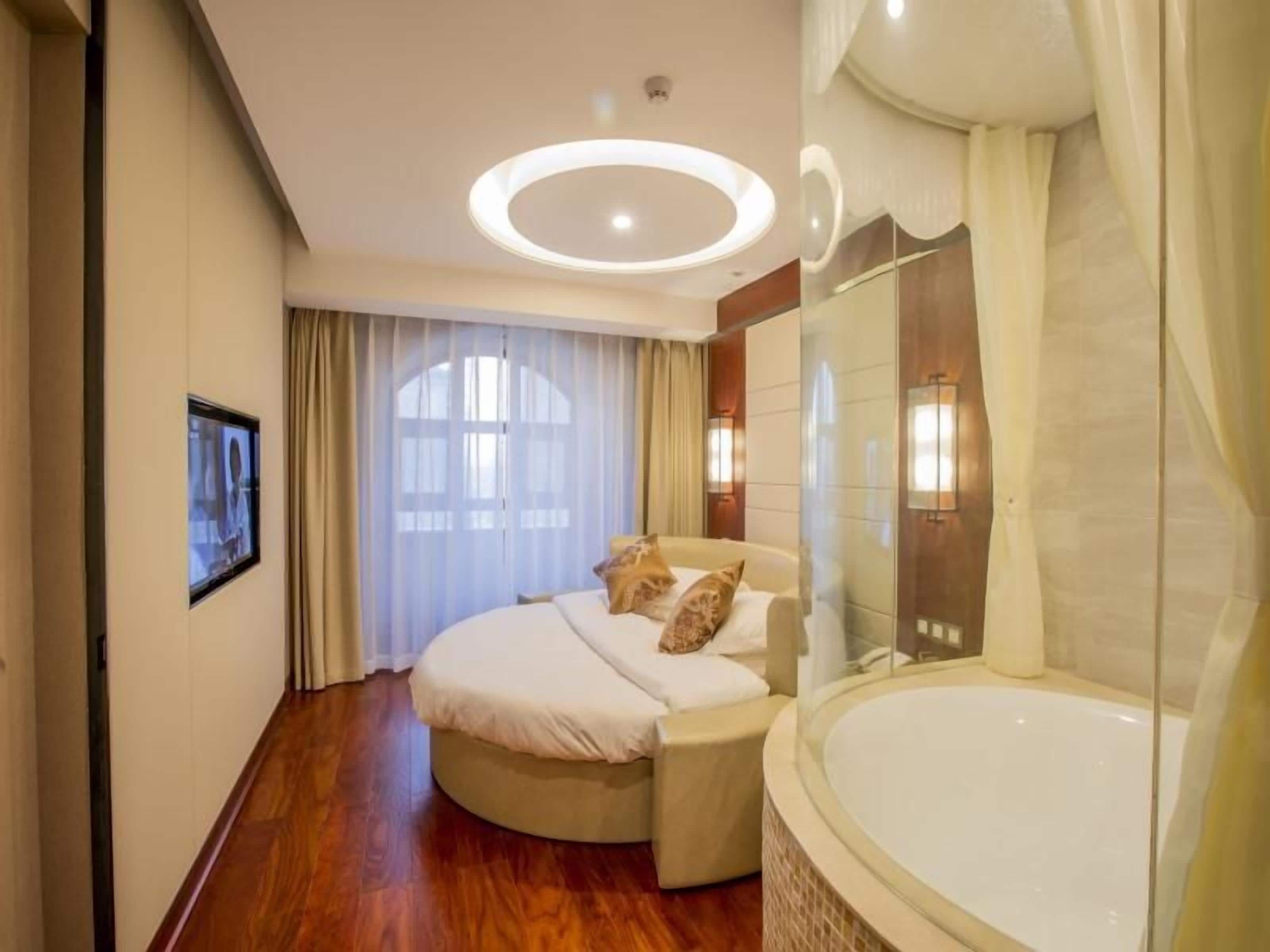 Une chambre d’hôtel avec un lit, une grande baignoire et une fenêtre avec des rideaux.